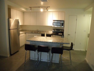 The kitchen of a typical unit at Roosevelt Point includes a stove, microwave and refrigerator.