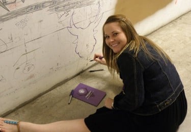 Becky Barber, GCU's social media specialist, paints the outline of an Antelope head on the graffiti wall connecting Comerica Theatre with its dressing rooms.