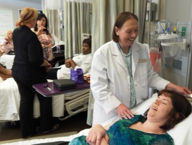 Cindy Westbrook (white jacket) assesses the health of "patient" Rebecca Nelson during the first day of GCU's residency for students in its onlin nurse practitioner program. The nurses developed a friendship even before meeting this week. 