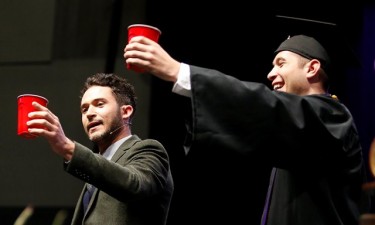 Commencement speaker Justin Willman (left) performs a magic trick on stage at Friday's ceremony. 