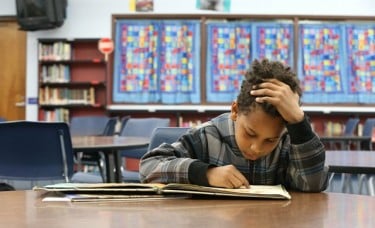 Sunset Elementary second grader Kyle Ward, 8, works through a book in the school library. In many Arizona classrooms, reading is a challenge for both students to learn and teachers to instruct.