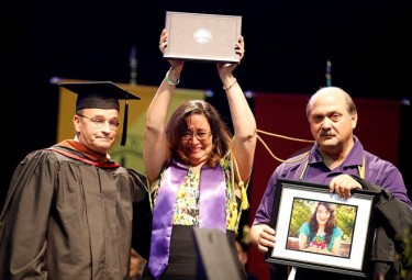 The Arena commencement crowd rose to its feet when Kathy and Eric Laneri, with (left) COFAP Dean Claude Pensis, came to the dais to accept the posthumous music degree on behalf of their daughter, Ashley, who died from injuries in a car accident in March.