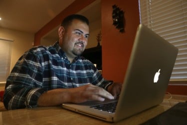 Zenon Castro works on assignments for his online master's degree in special education at home on his laptop. 