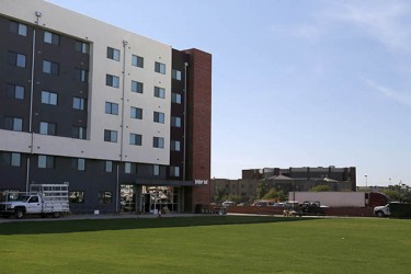 Juniper Hall, one of four six-story residence halls at The Grove, towers over the new sod between the four buildings.