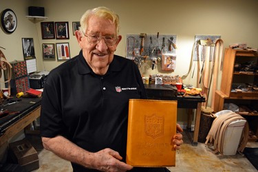 Alumnus Stanley Fred Hawkins displays the leather bound cover that he created, at the NFL's request, for the record book of Denver Broncos quarterback Peyton Manning. 