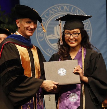 Dr. Randy Gibb, dean of the Colangelo College of Business, rewards a student with her diploma. (Photo by Darryl Webb)