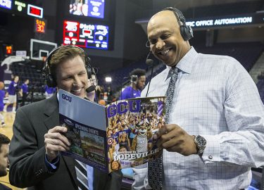 The broadcast team on GCU basketball telecasts, Barry Buetel (left) and Scott Williams, took a look at GCU Magazine before Monday's game. (Photo by Darryl Webb)